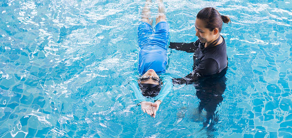 Woman teaching boy how to swim